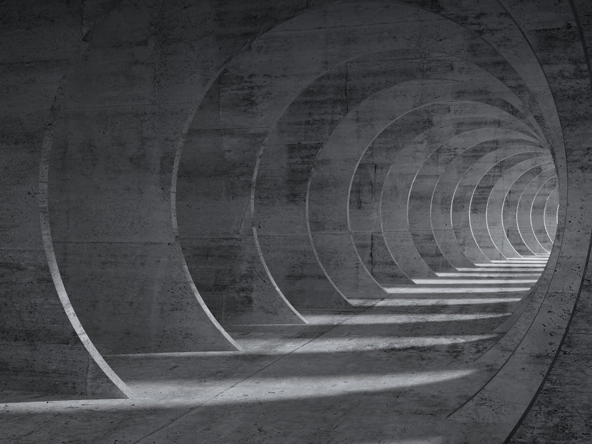 Concrete tunnel with repeating circular openings and light streaming across the floor.