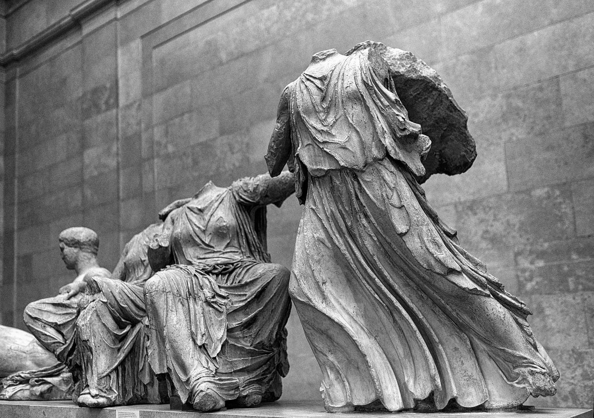 Pair of headless statues in black and white inside a museum.