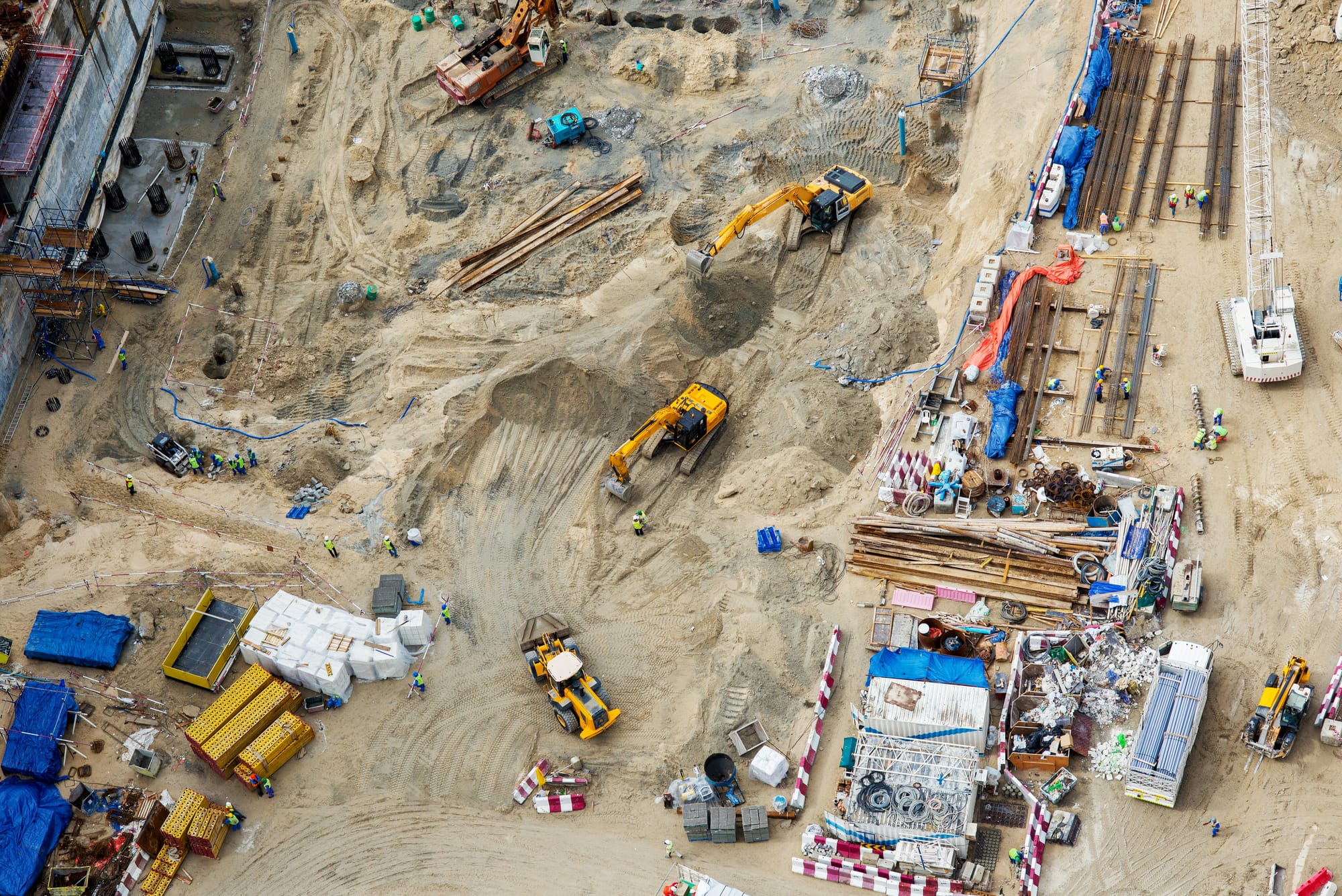 Aerial view of a large construction site with excavators, heavy equipment and workers.