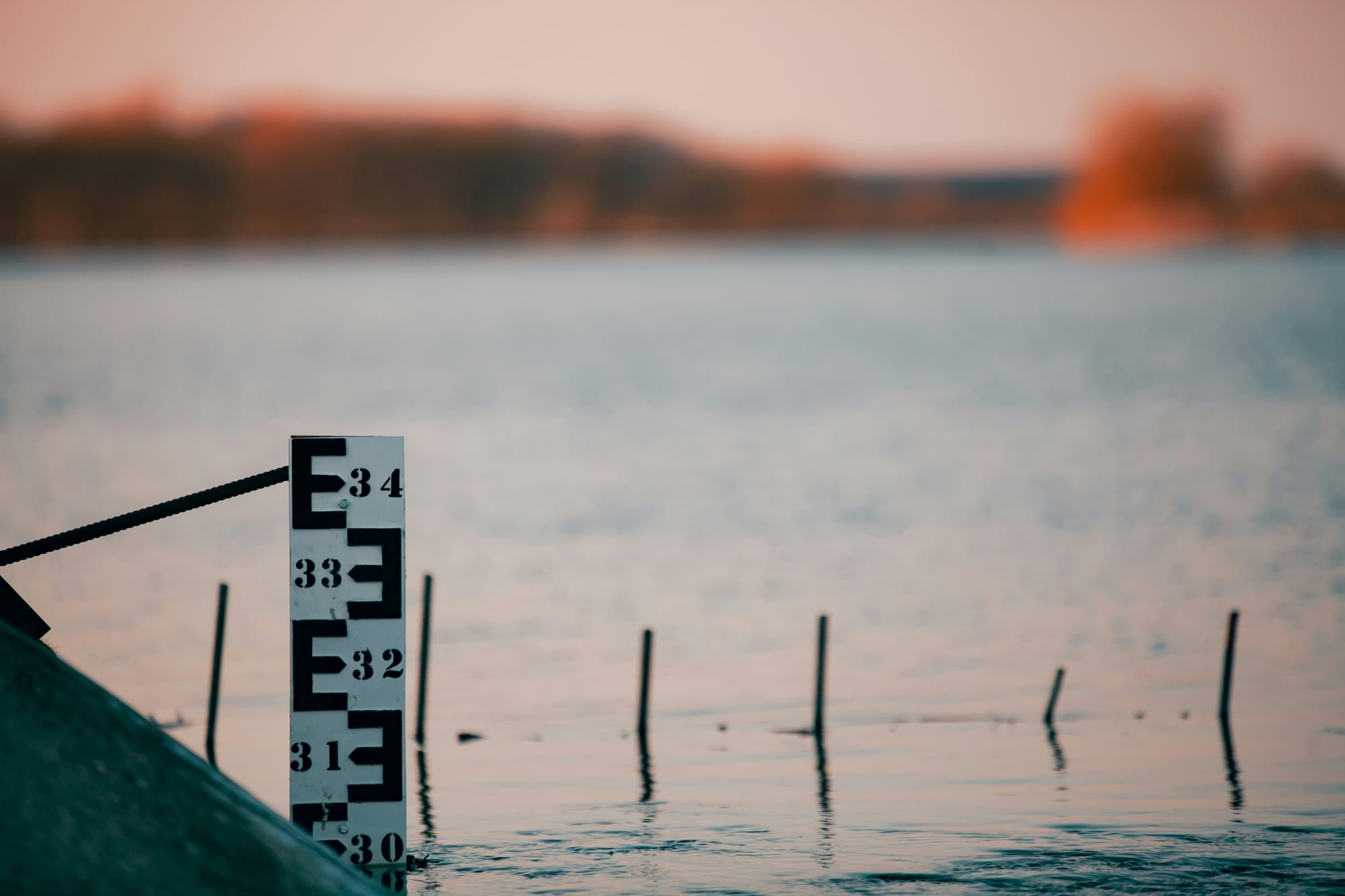 Water level gauge in a calm lake at sunset.
