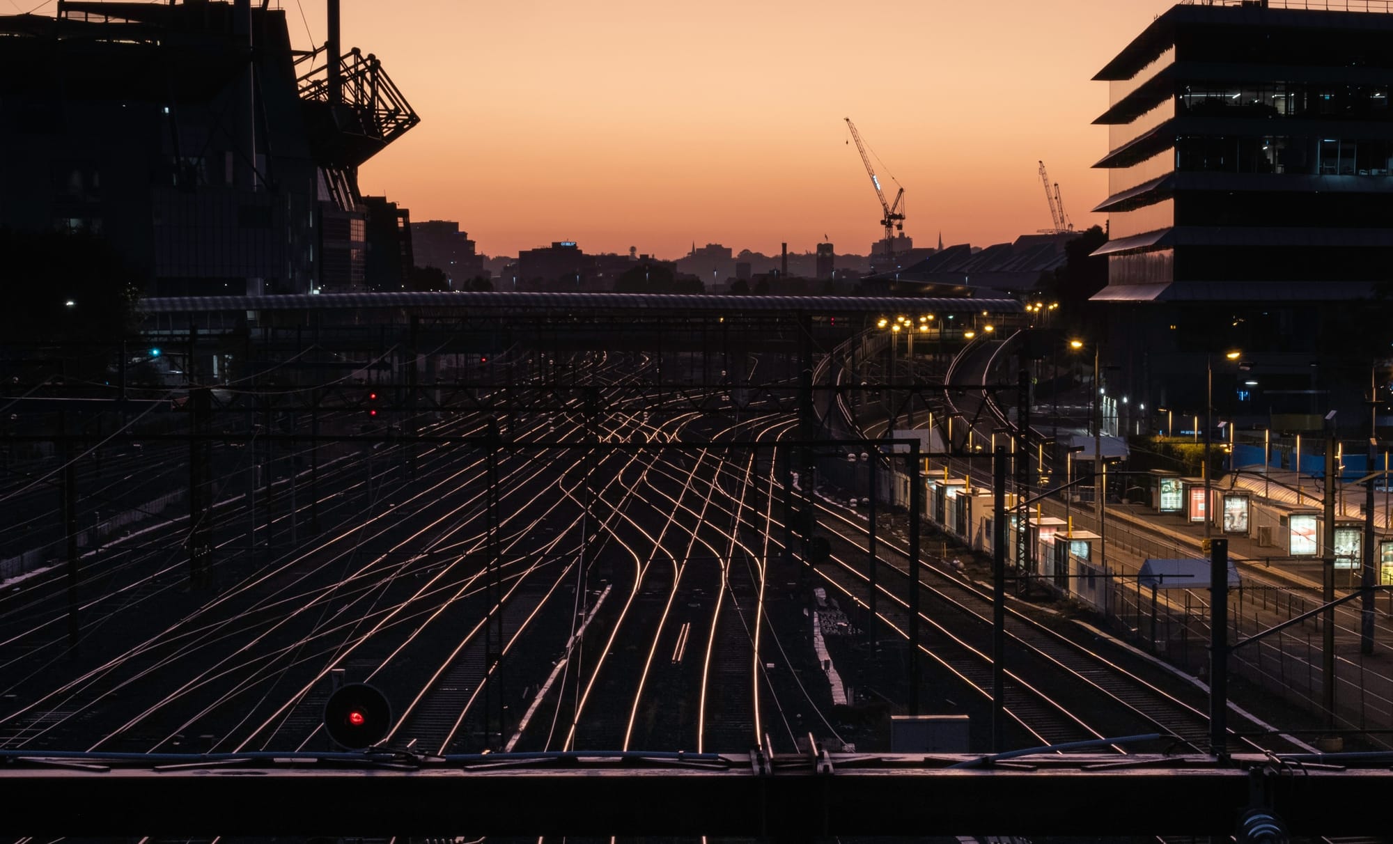 Railway tracks branching in multiple directions through a city at dusk.