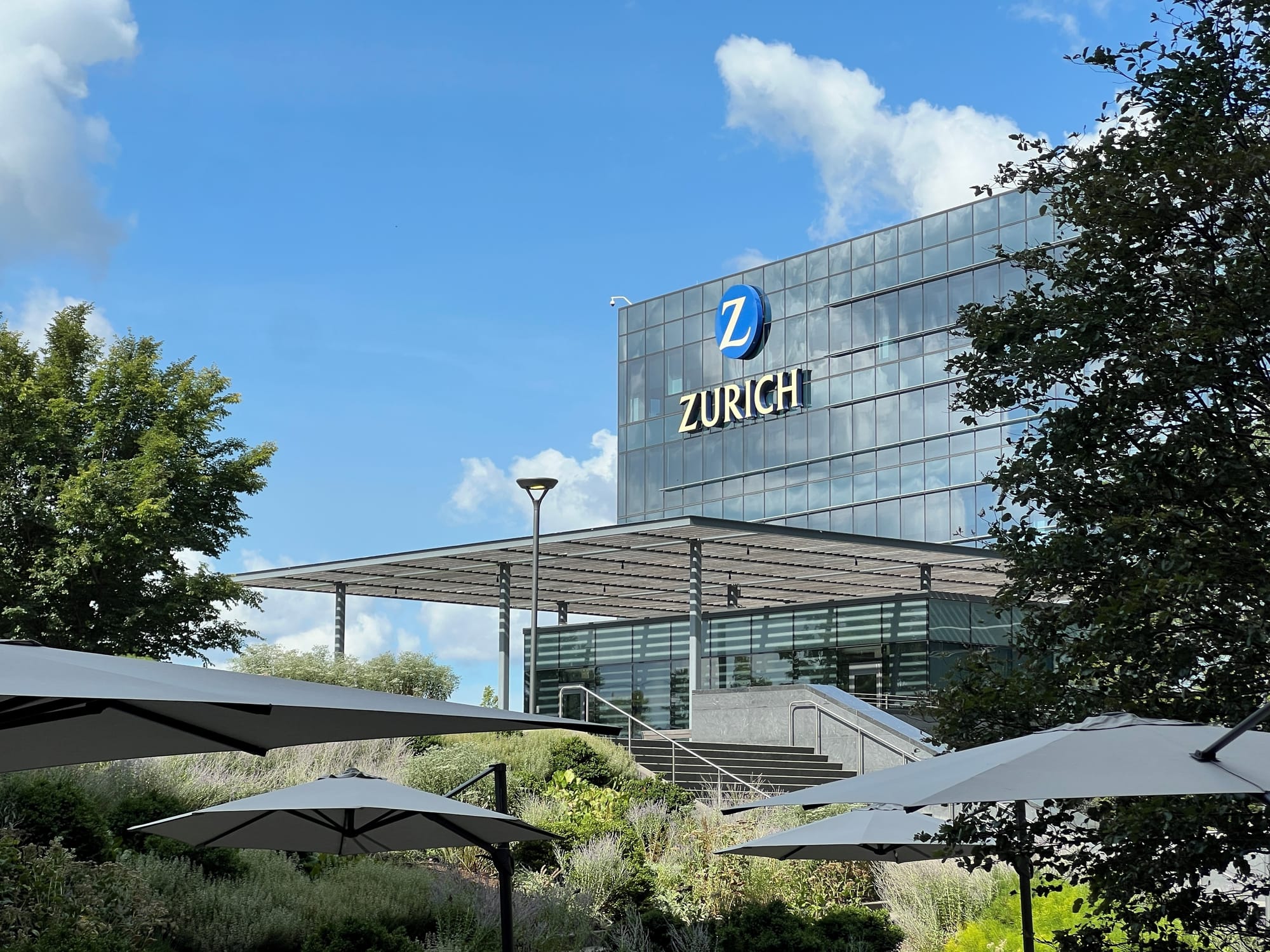 Patio with glass building with Zurich logo on it.