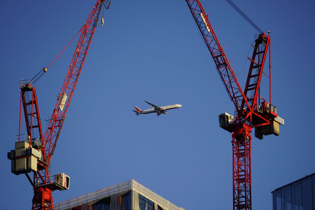 Plane flying over constructions site with Cranes