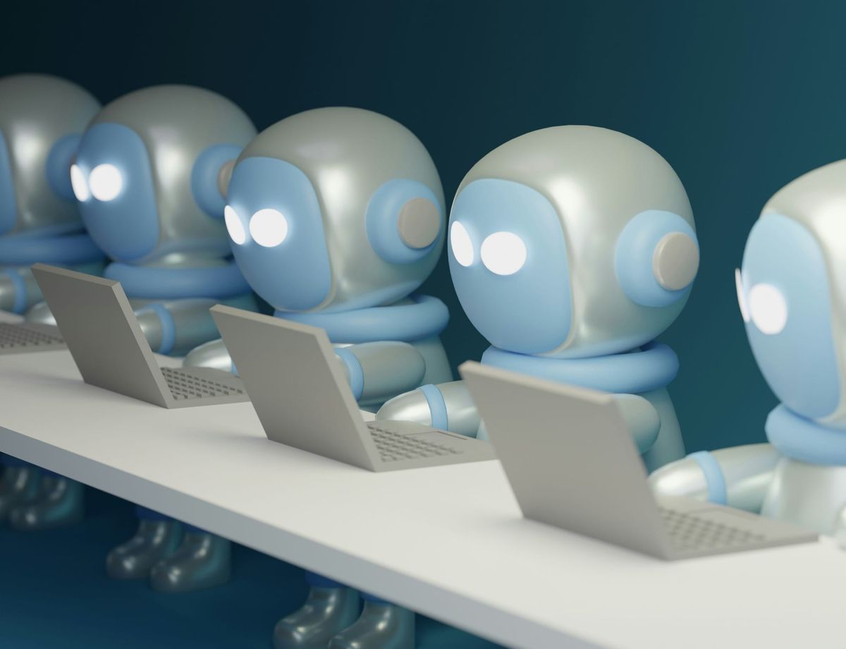 Row of cartoon robots sitting at a table, each working on a laptop against a teal background.