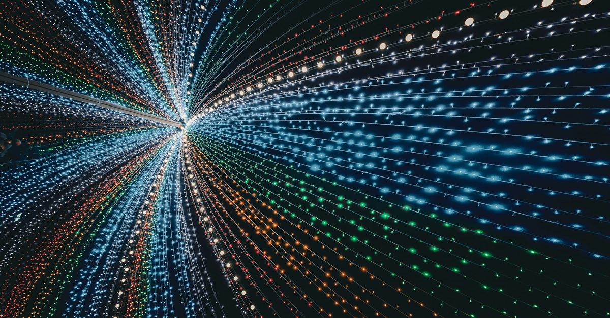 Abstract burst of multicolored light trails converging toward a vanishing point on a dark background