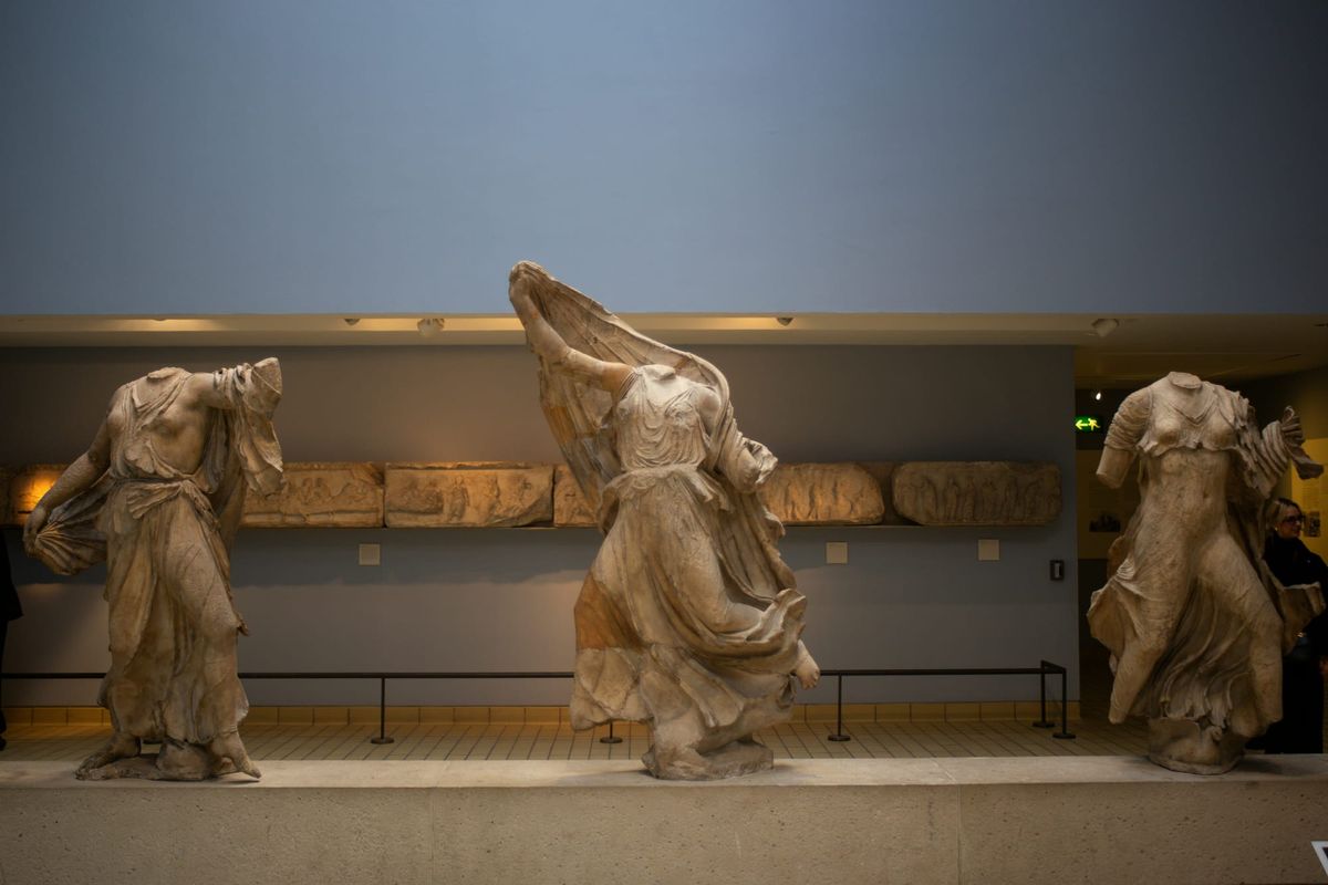 Three headless ancient marble statues displayed in a museum