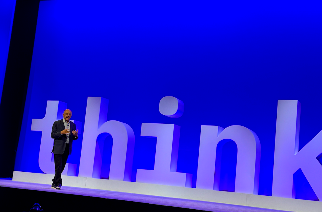 IBM CEO Arvind Krishna walking on stage with think logo behind him.