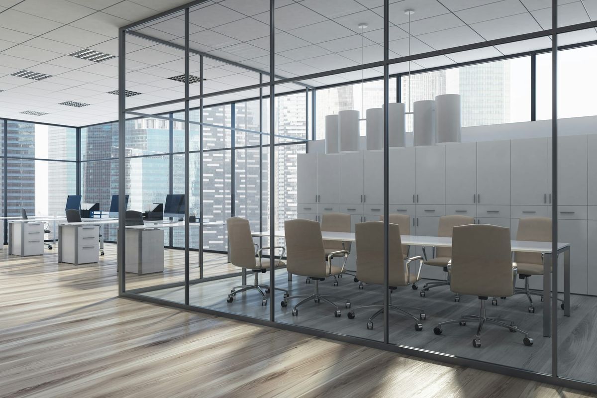 Empty corporate office with vacant conference room and unoccupied desks overlooking a city skyline.