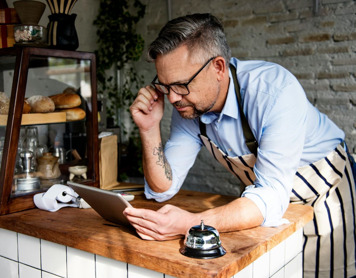 Cafe owner pours over iPad with a look of confusion