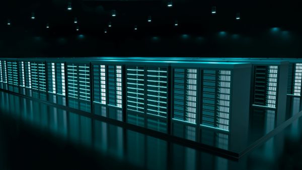 Rows of illuminated server racks in a dark, high-tech data center, glowing in teal light under ceiling spotlights.