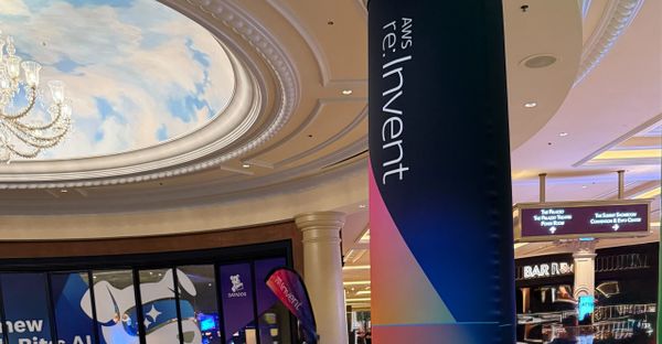 A large AWS re:Invent banner stands on a pillar in a corridor in the Venetian Hotel in Las Vegas, with a painted sky ceiling,