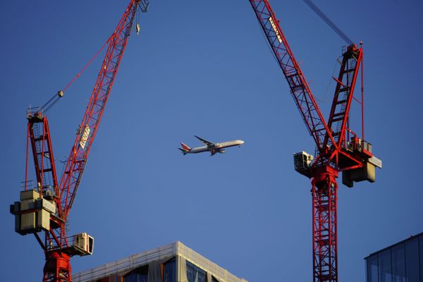 Plane flying over constructions site with Cranes