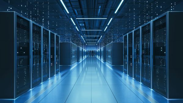 Rows of illuminated server racks inside a modern data center, blue LED lighting reflecting off a polished floor with overhead cables and conduits visible along the ceiling.