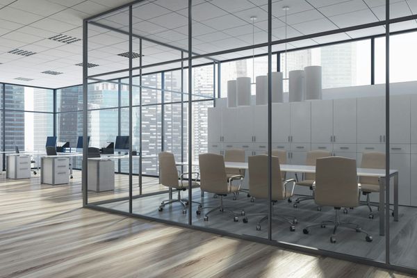 Empty corporate office with vacant conference room and unoccupied desks overlooking a city skyline.