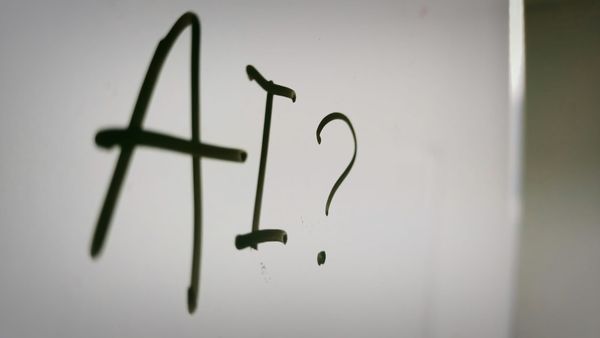 "AI?" written on a whiteboard in dark marker, slightly out of focus.