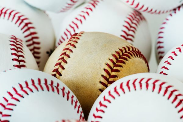 A group of white baseballs with a scuffed one among them.