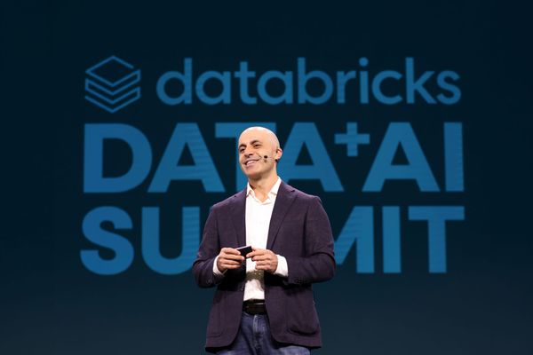 Databricks CEO Ali Ghodsi in front of the databricks Data + AI Summit sign