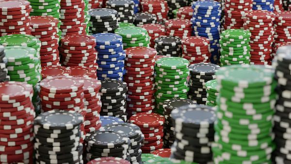 Piles of green, red, black and blue poker chips of various heights.