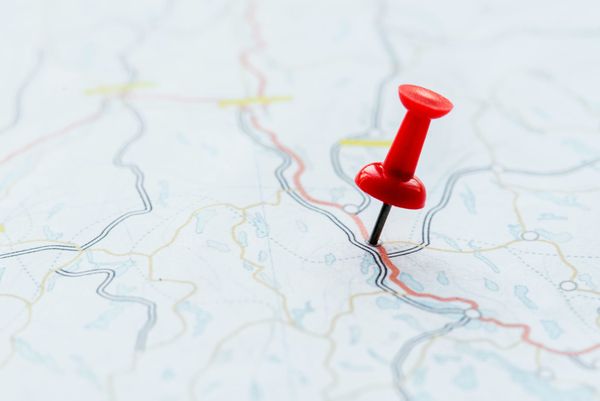 Close-up or a road map with a red push pin at the destination.