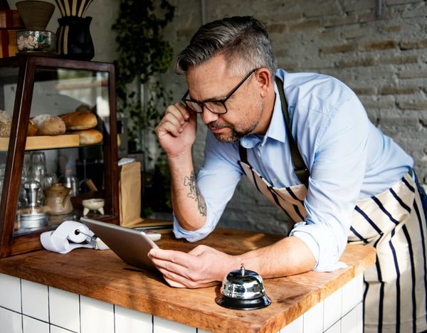 Cafe owner pours over iPad with a look of confusion