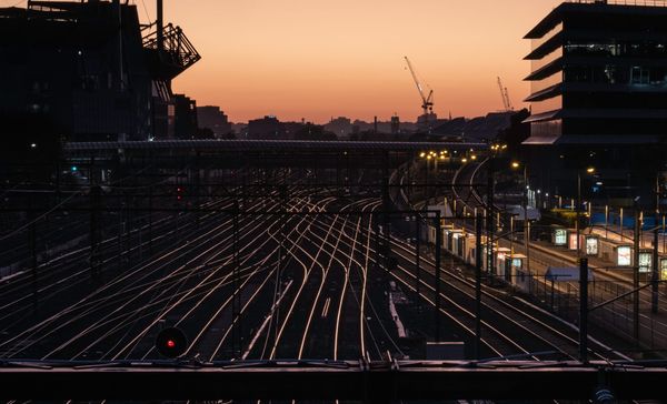 Railway tracks branching in multiple directions through a city at dusk.