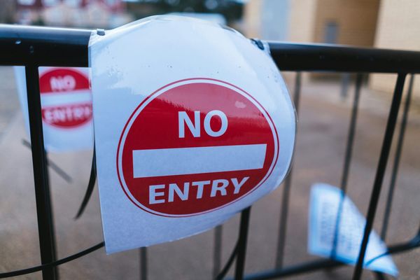 No Entry sign on a black barrier fence.