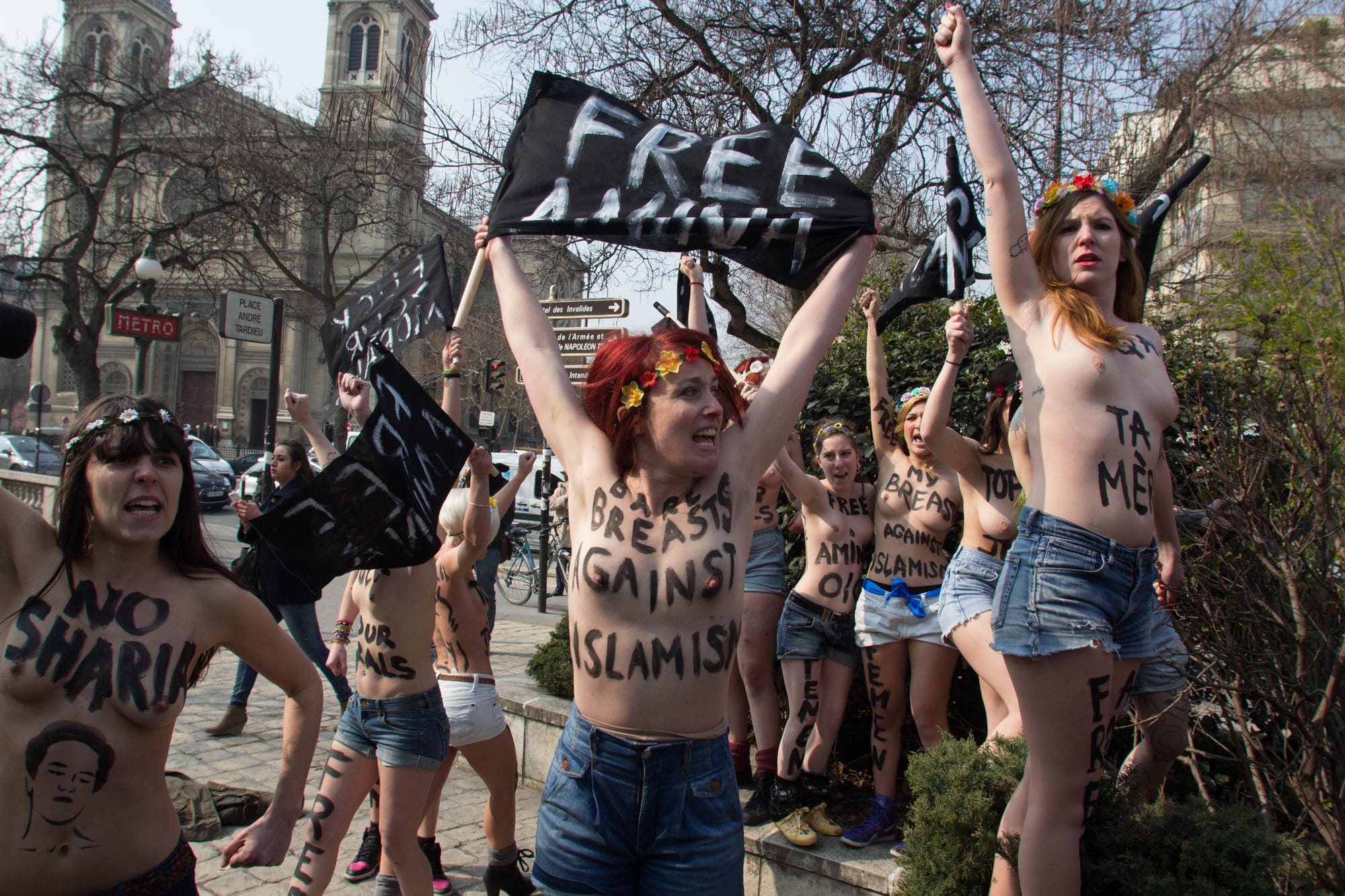Women protesting without their tops on and with writing daubed across their chests in black paint