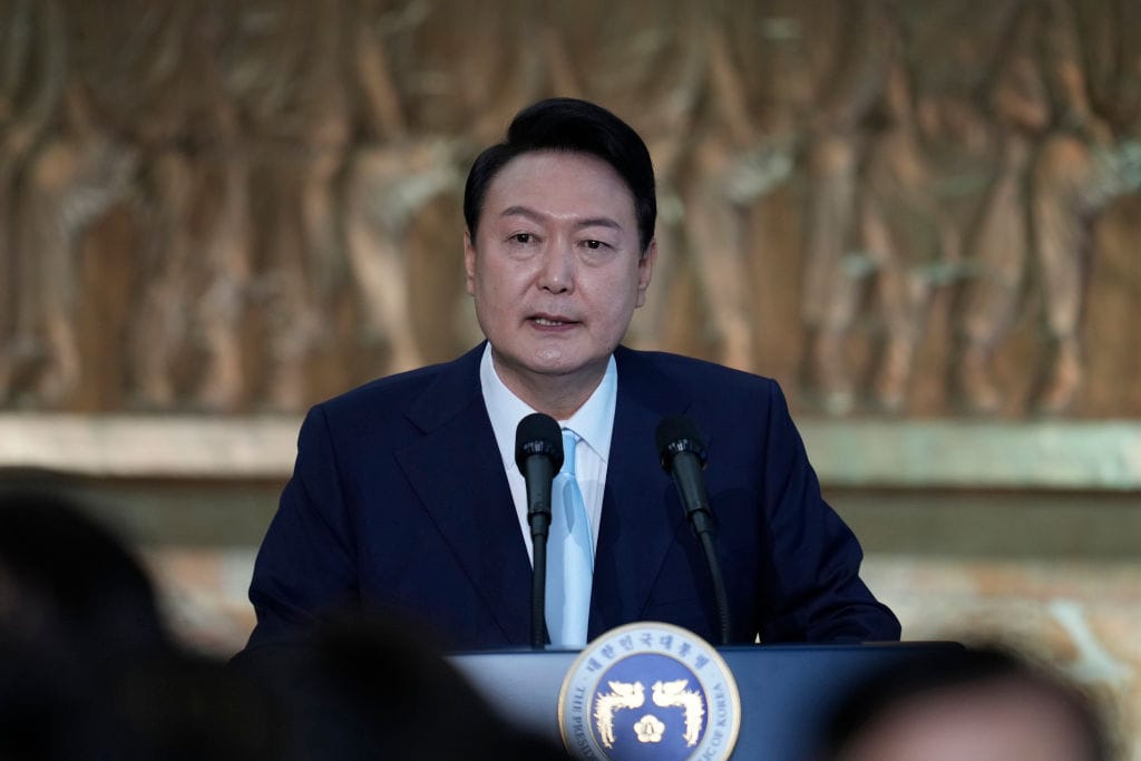 South Korean President dressed in a blue suit stands at a podium.