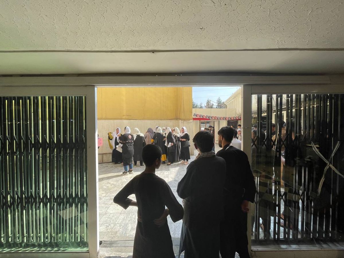 Photo of a group of women staging a protest as men stand in a doorway