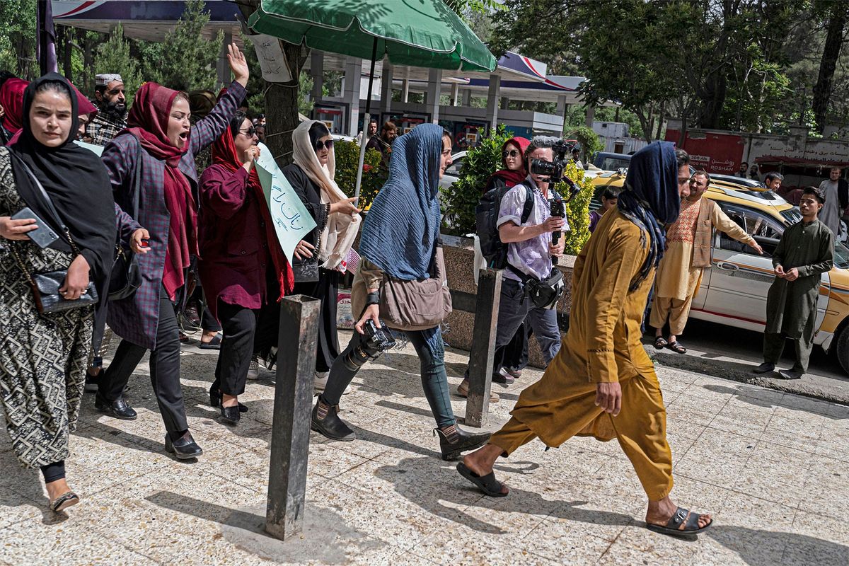 A photo of protesters holding signs and chanting