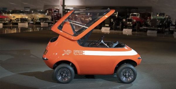 side profile of orange GM XP 512E electric car with its canopy open