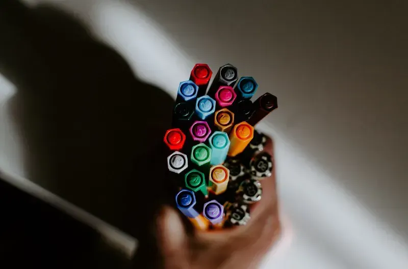 Hand holding a fistful of colored pens, a metaphor for sorting tasks by priority