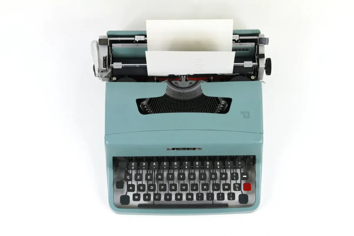 Vintage teal Olivetti typewriter with blank paper, nodding to nostalgic writing sounds