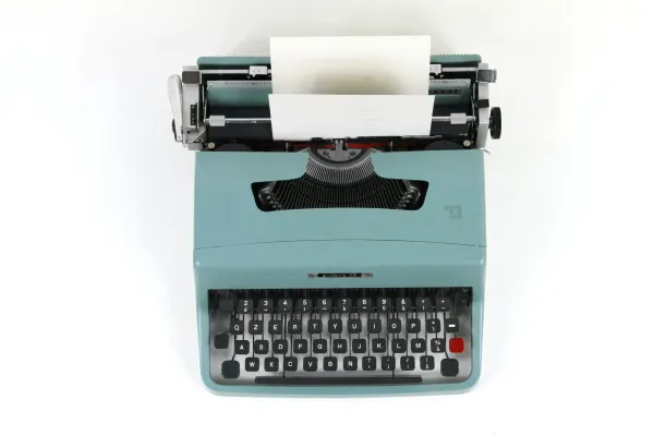 Vintage teal Olivetti typewriter with blank paper, nodding to nostalgic writing sounds