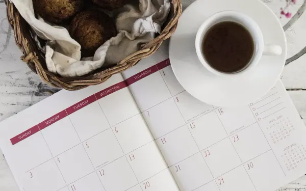 Paper calendar beside coffee and pastries evoking a weekly review ritual