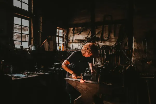 Blacksmith hammering glowing metal at an anvil, illustrating software craftsmanship