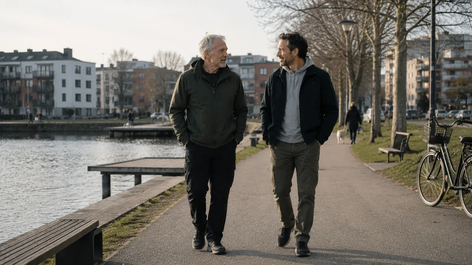 Two men, one older and one younger, walking together along a canal path.