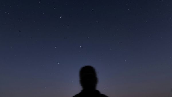 Silhouette of a man stands blurry in front of a starry night sky