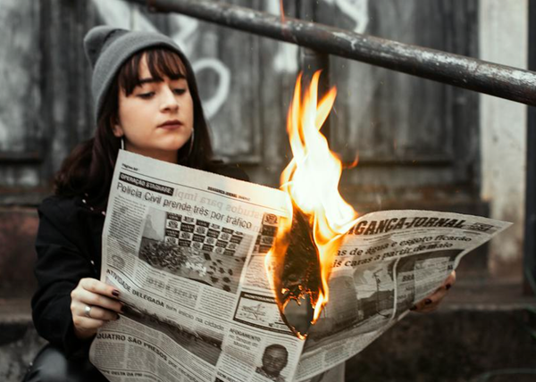 a young person reading a newspaper that is on fire