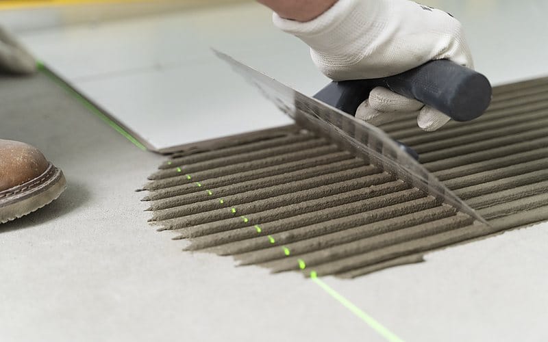 施工人員以鏝刀塗佈黏著劑鋪設地磚