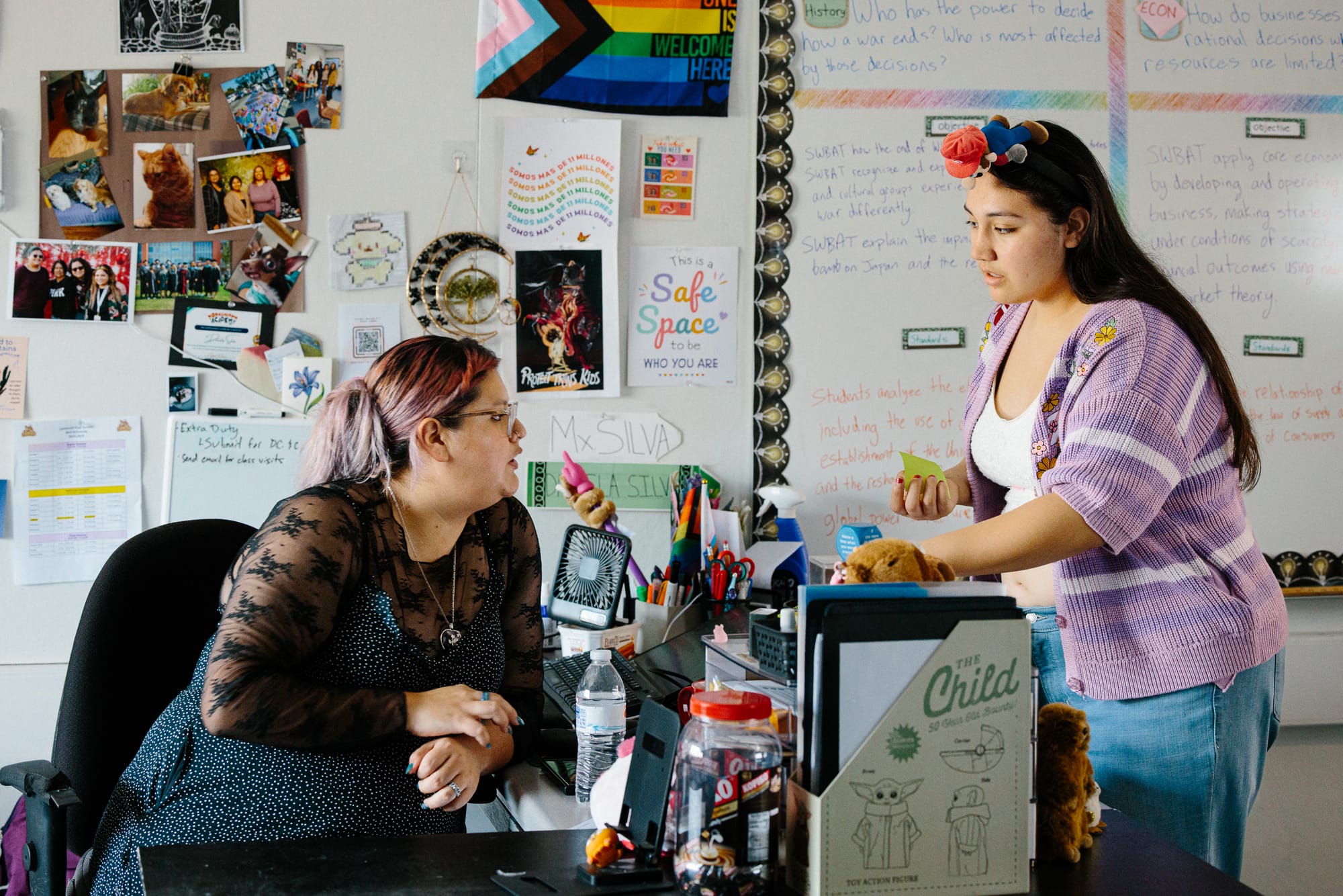 Daniela Silva Álvarez sentada en su escritorio, conversando con uno de sus estudiantes de preparatoria en Lynwood, California. Foto de Stella Kalinina para The Fault Line.