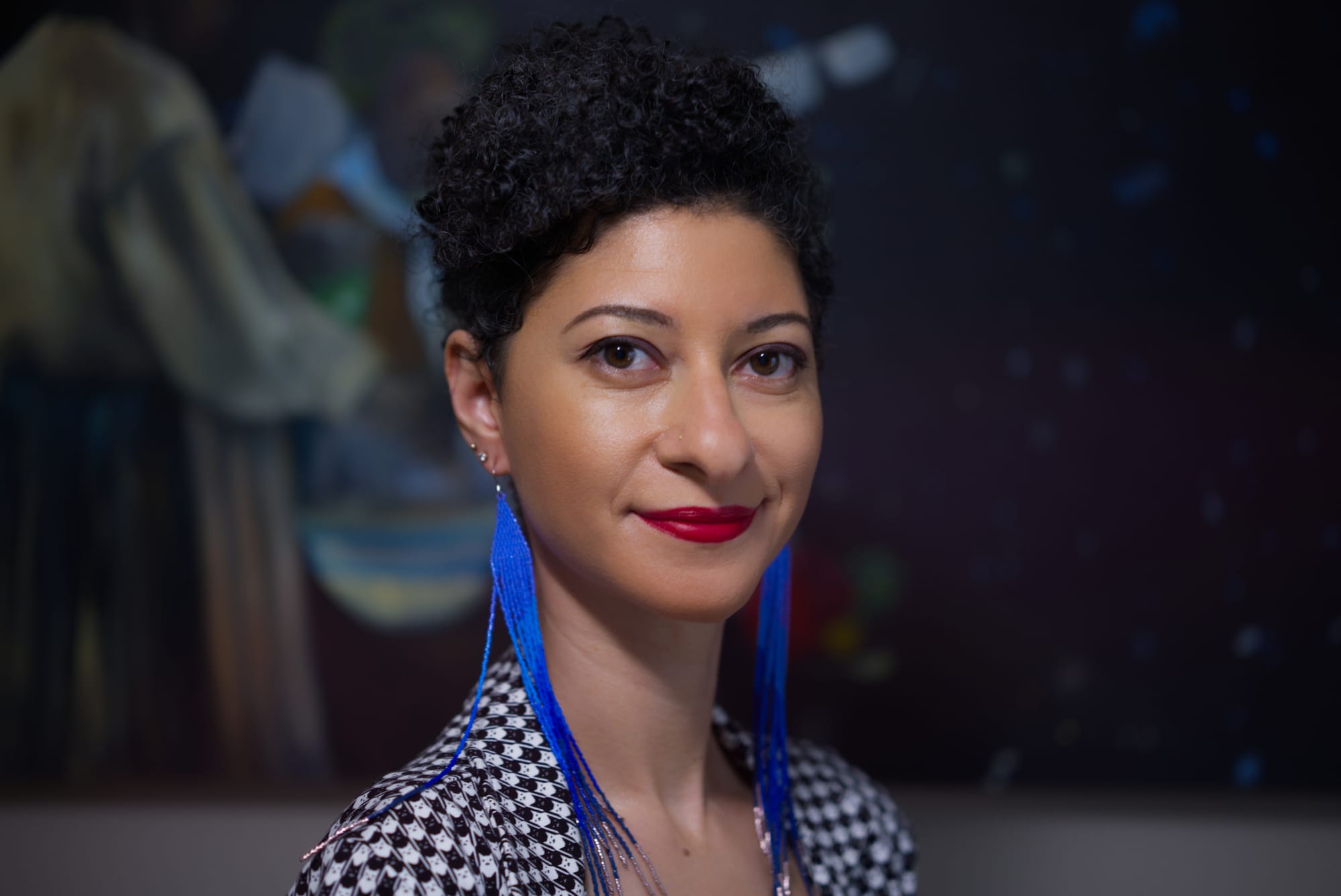 A smiling Chanda Prescod-Weinstein, author of "The Edge of Space-Time," wears long cobalt blue earrings. Photo courtesy of Prescod-Weinstein.