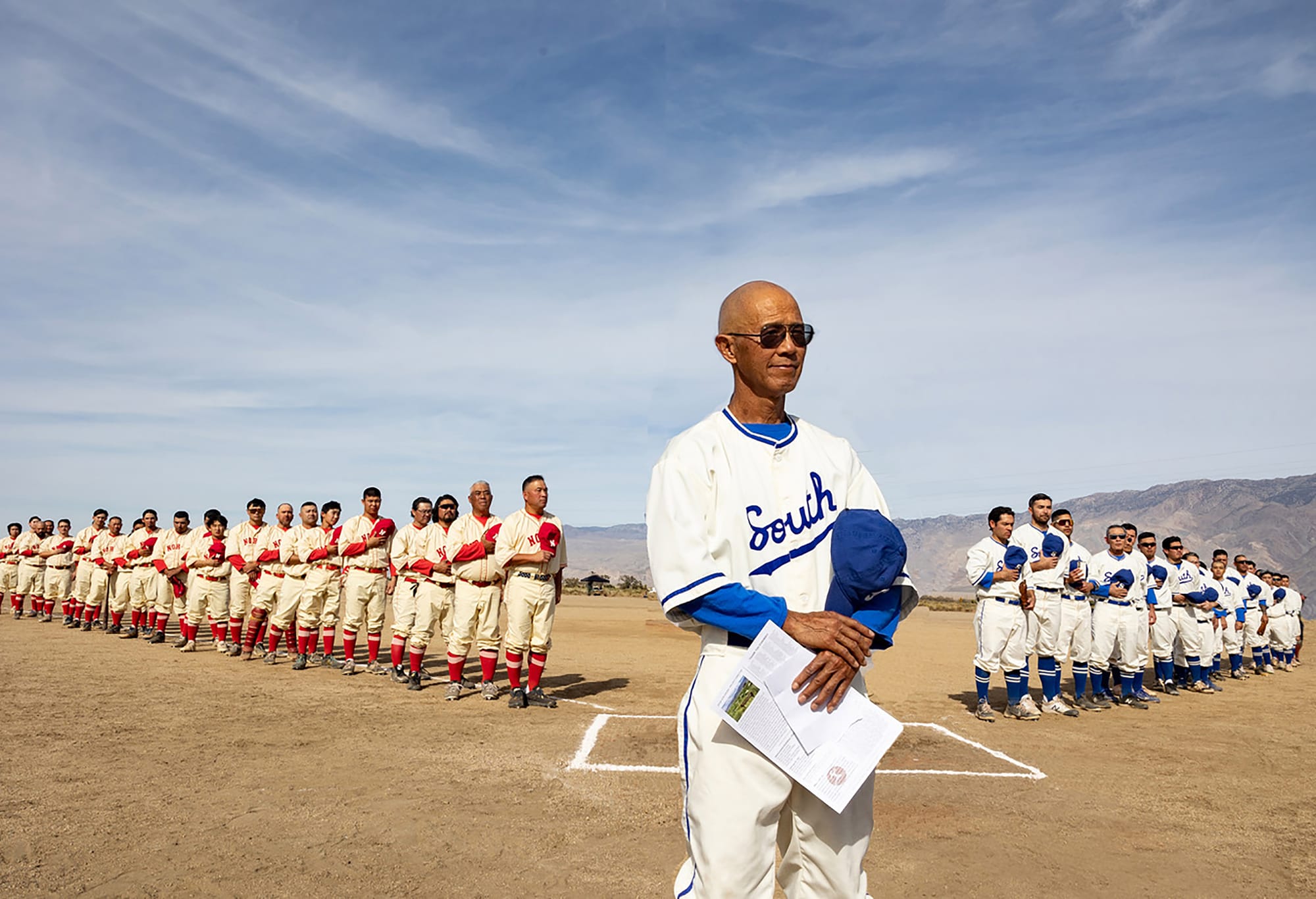 Dan Kwong and other baseball players stand on the restored baseball field at the Manzanar National Historic Site in 2024. Photo by Aaron Rapoport Photography. Photo courtesy of Great Leap. 