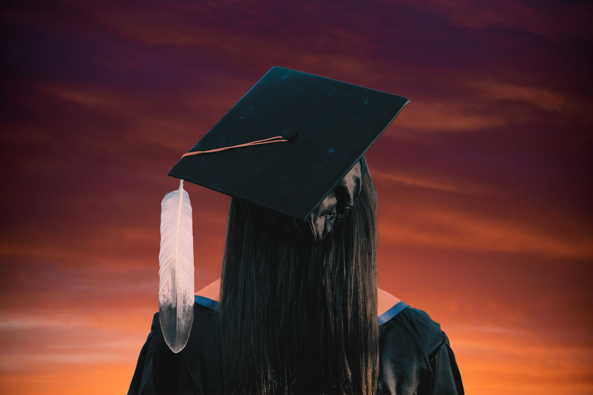 A photo illustration of a graduate from behind wearing a cap with a feather tassel. She stands in front of an orange and purple sky. Photo illustration by Anthony Nittle for The Fault Line.