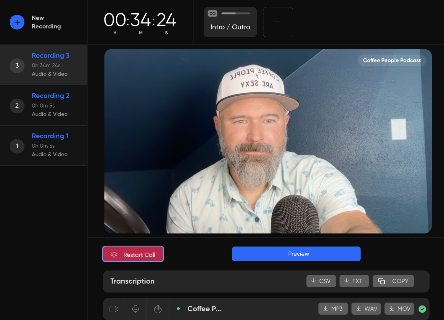 A screenshot of a grey-bearded gentleman in a casual short-sleeved collared shirt (blue with bicycles printed on it) smiles at the camera from behind the top of a microphone in front of a blue wall while recording a podcast. he's wearing a white baseball cap that says "Coffee People Are Sexy."