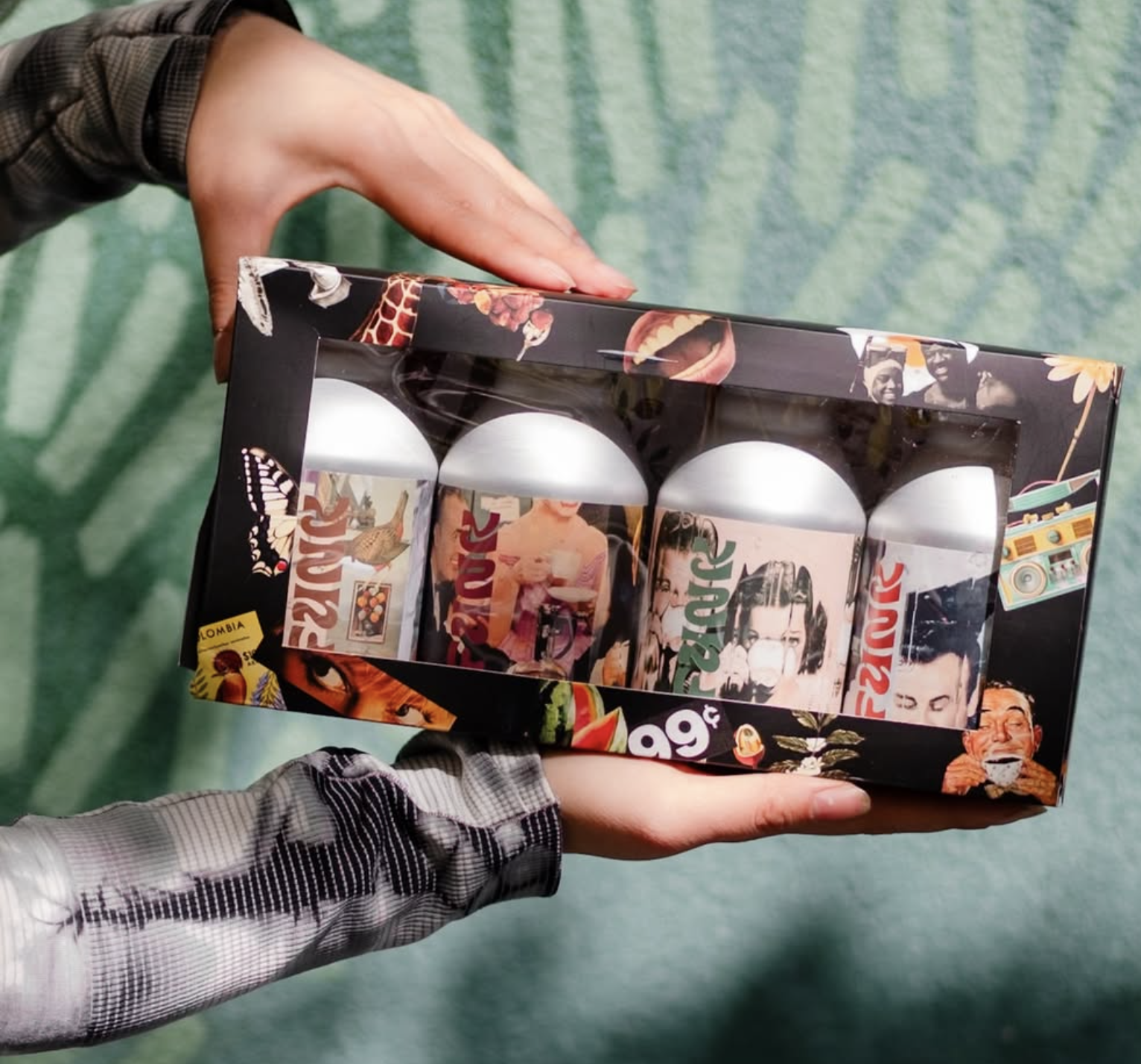 A close up of packaging. Cans with wrapped sticker labels inside of an illustrated box with a clear cellophane window.
