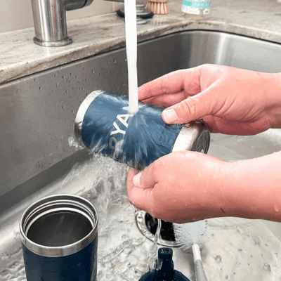 Person rinsing a wide-mouth stainless steel water bottle