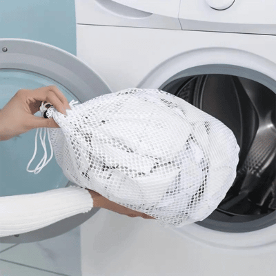 Mesh laundry bag being placed in a washing machine