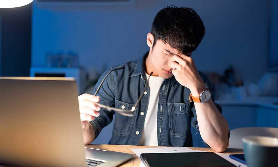 Man experiencing eye strain while working at a computer