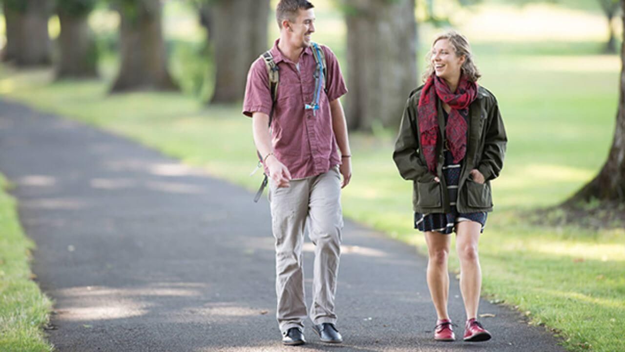 Man and a woman wearing barefoot shoes while walking a pathway